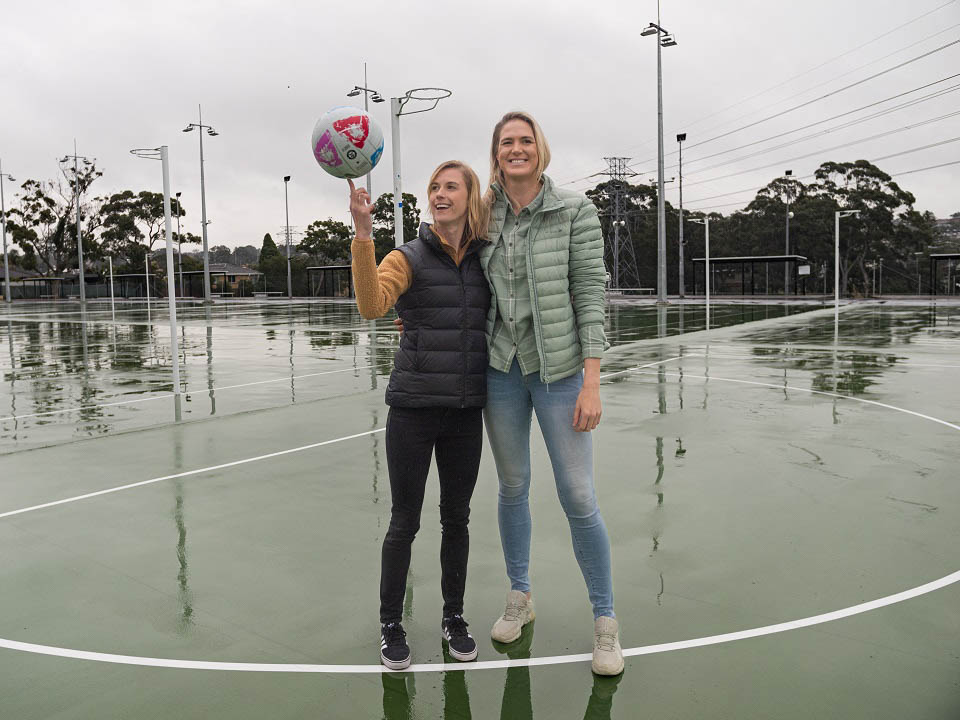 Kate standing on a court with netballer Caitlin Bassett