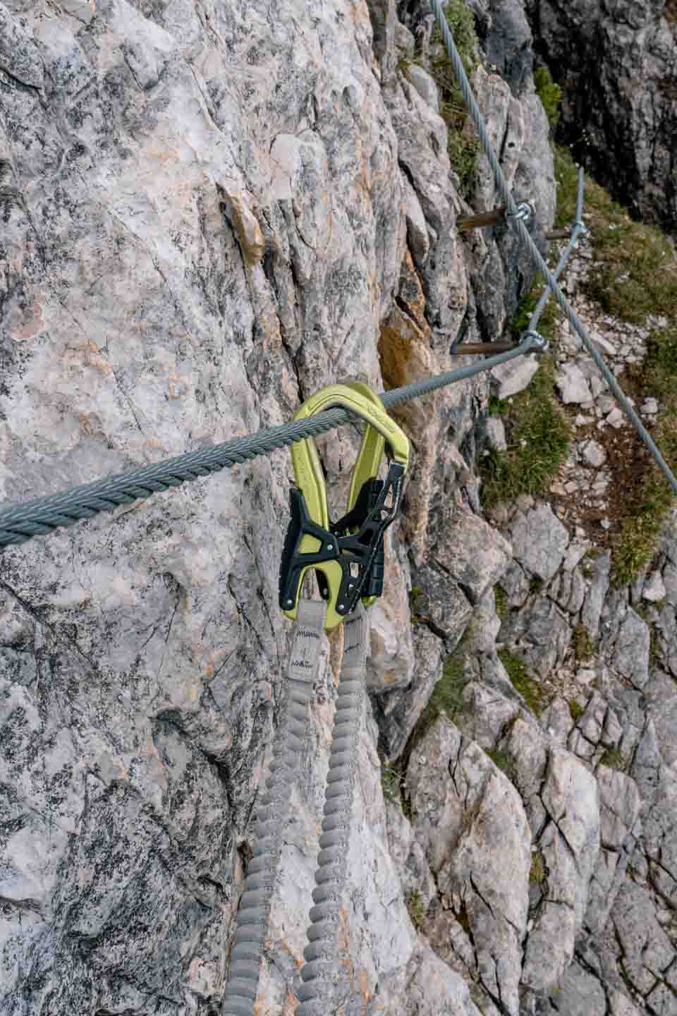 Close up of clipping Via Ferrata set carabiners onto the wire