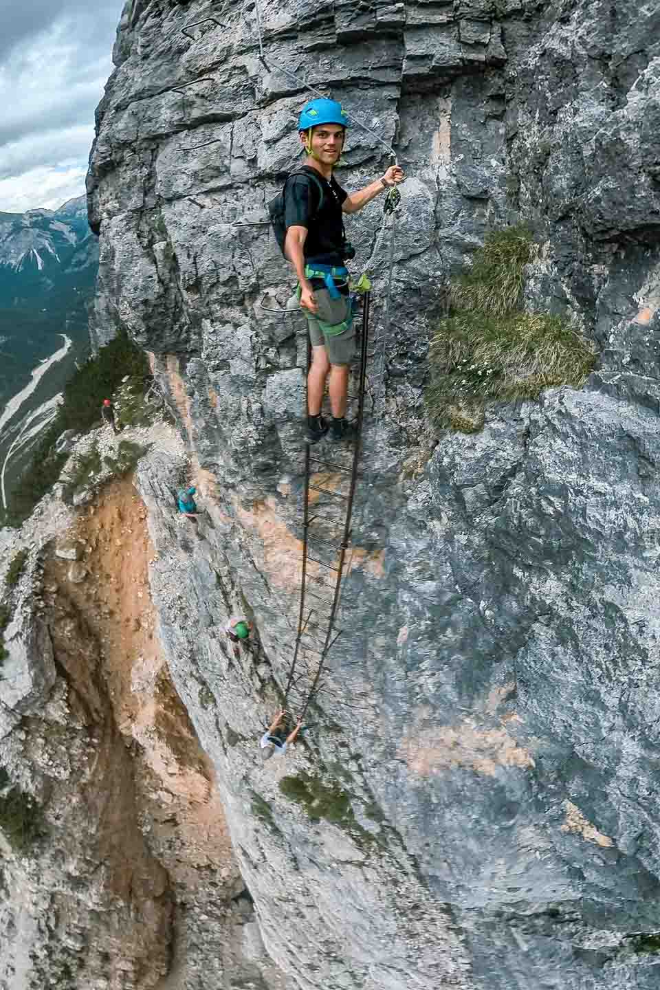 Wide fisheye shot of Zach Bostock on steel ladders to the summit